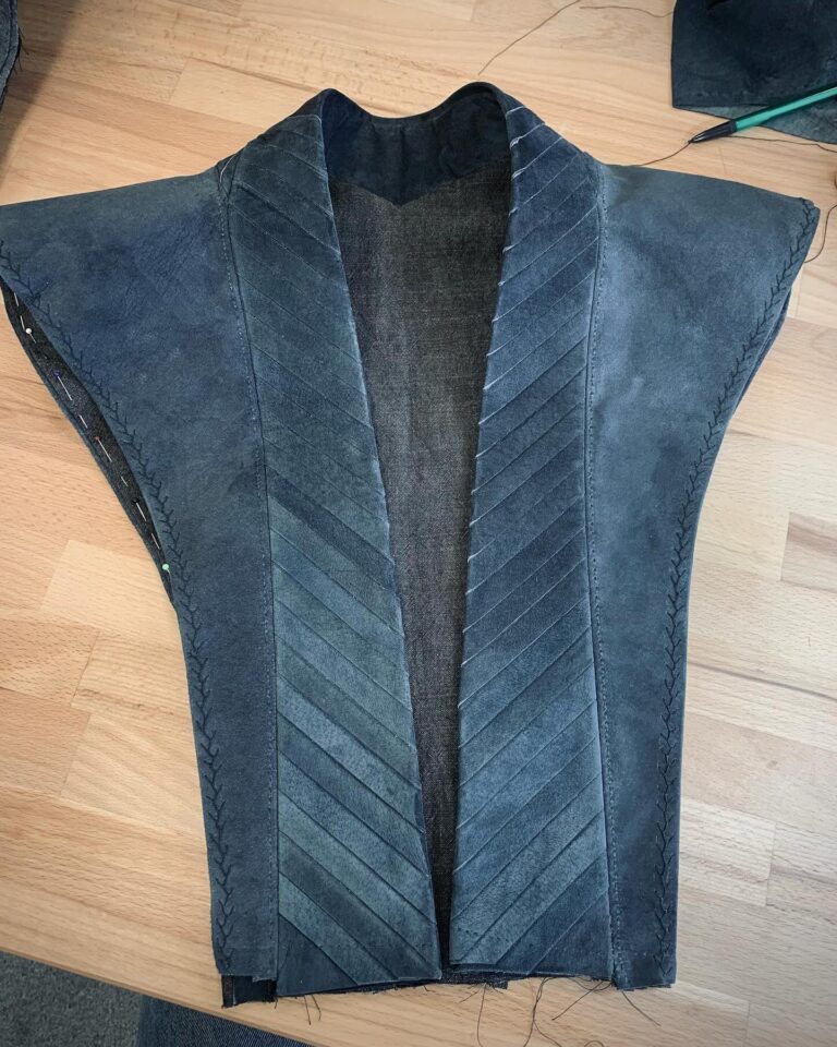 Rhaenys Targaryen’s suede coat laid flat mid-construction, its front built from chevron-cut panels joined by hand-finished seams